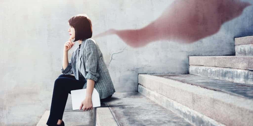 Woman sitting on stirs with superhero cape