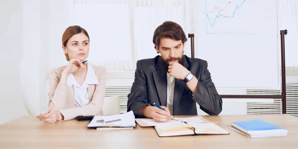 man and woman sitting at desk in conflict